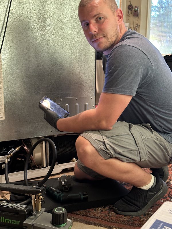 Uhauz technician inspecting a GE Profile refrigerator's sealed system during the diagnostic visit